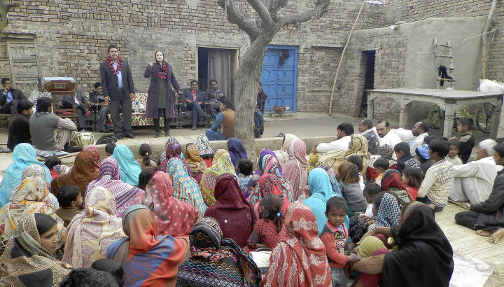 Freiluft-Gottesdienst in Pakistan, bunt gekleidetes Publikum
